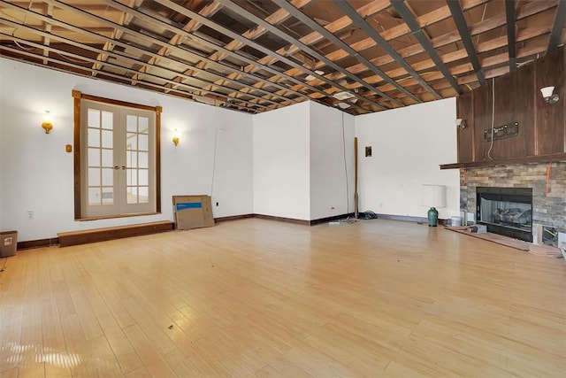 unfurnished living room with light hardwood / wood-style floors, french doors, and a fireplace