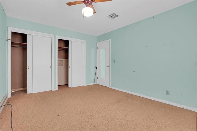 unfurnished bedroom featuring multiple closets, ceiling fan, and carpet floors