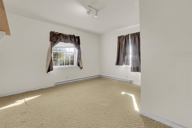 unfurnished room featuring track lighting, carpet, and a baseboard heating unit