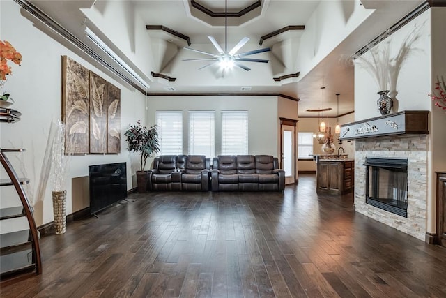 unfurnished living room with dark wood-type flooring, ornamental molding, a fireplace, and a raised ceiling