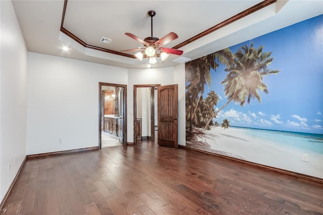 spare room with ceiling fan, dark wood-type flooring, crown molding, and a raised ceiling