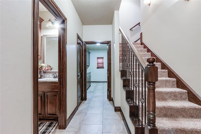 stairs featuring tile patterned flooring and sink