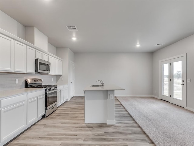 kitchen with appliances with stainless steel finishes, a sink, visible vents, and decorative backsplash