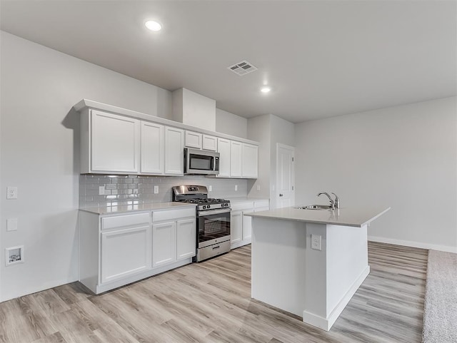 kitchen with appliances with stainless steel finishes, light wood-type flooring, visible vents, and a sink