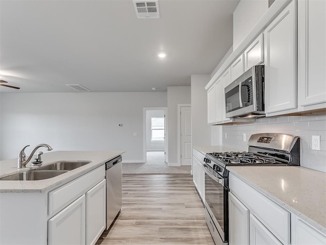 kitchen with visible vents, decorative backsplash, stainless steel appliances, white cabinetry, and a sink