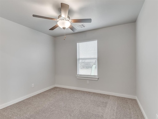 empty room featuring carpet floors, visible vents, baseboards, and a ceiling fan