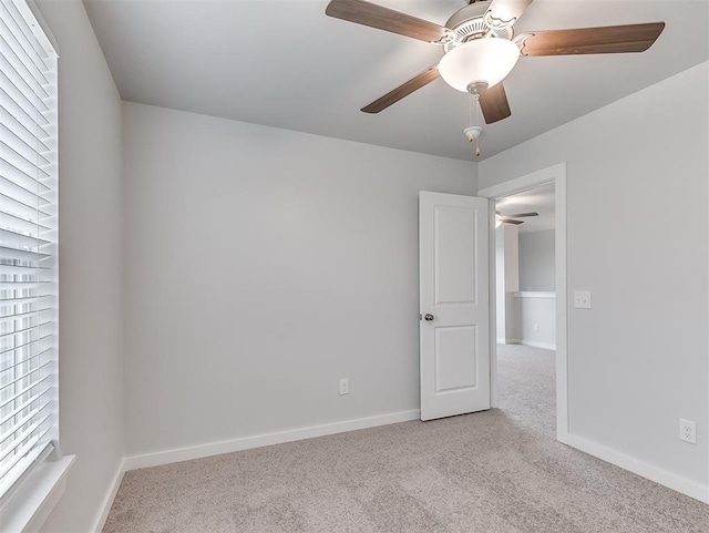 empty room featuring carpet flooring, a ceiling fan, and baseboards