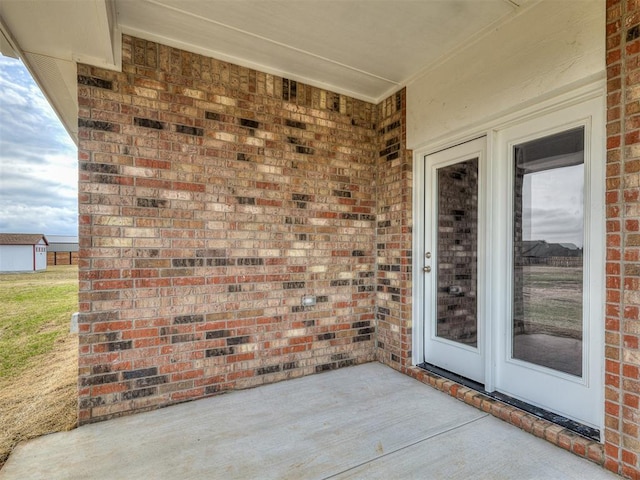 property entrance featuring a patio and brick siding