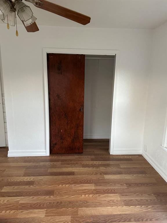 unfurnished bedroom with ceiling fan, dark wood-type flooring, and a closet