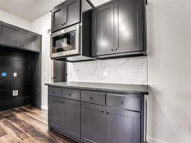 kitchen featuring tasteful backsplash, stainless steel microwave, and dark hardwood / wood-style flooring