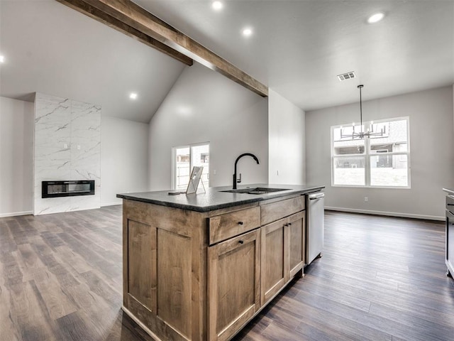 kitchen with sink, decorative light fixtures, dishwasher, a premium fireplace, and a kitchen island with sink