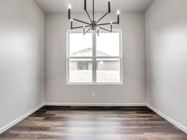 unfurnished room featuring a notable chandelier and dark hardwood / wood-style floors