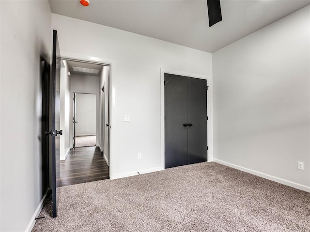 unfurnished bedroom with dark carpet, a closet, and ceiling fan