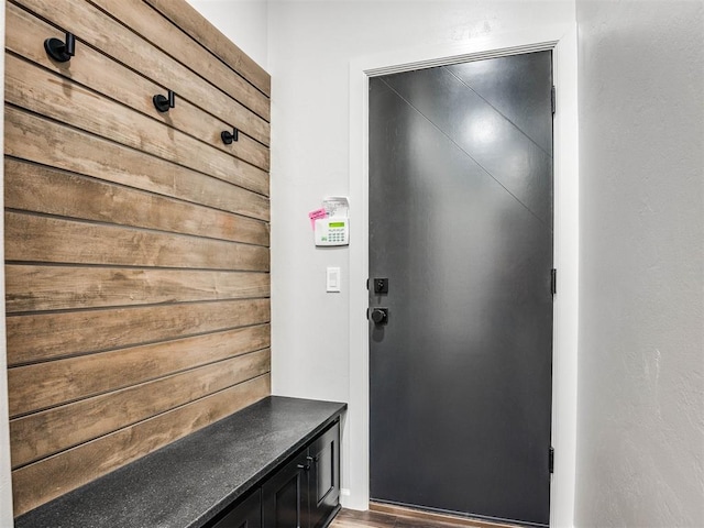 mudroom featuring wood-type flooring and wood walls