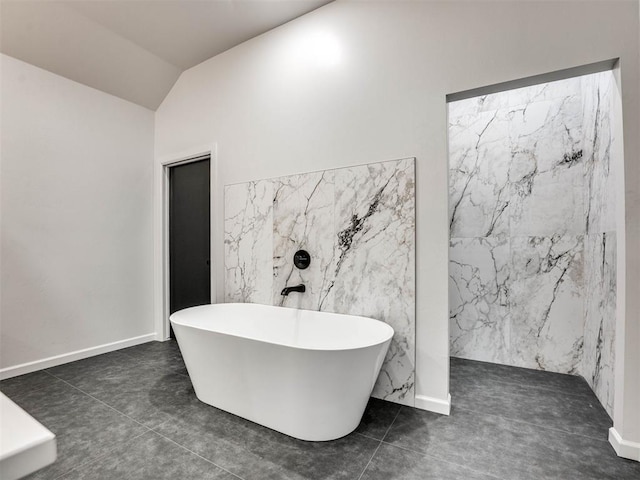 bathroom with tile patterned flooring, vaulted ceiling, and a tub to relax in