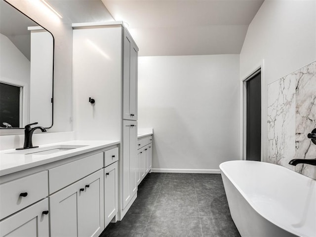 bathroom featuring a tub to relax in, lofted ceiling, and vanity