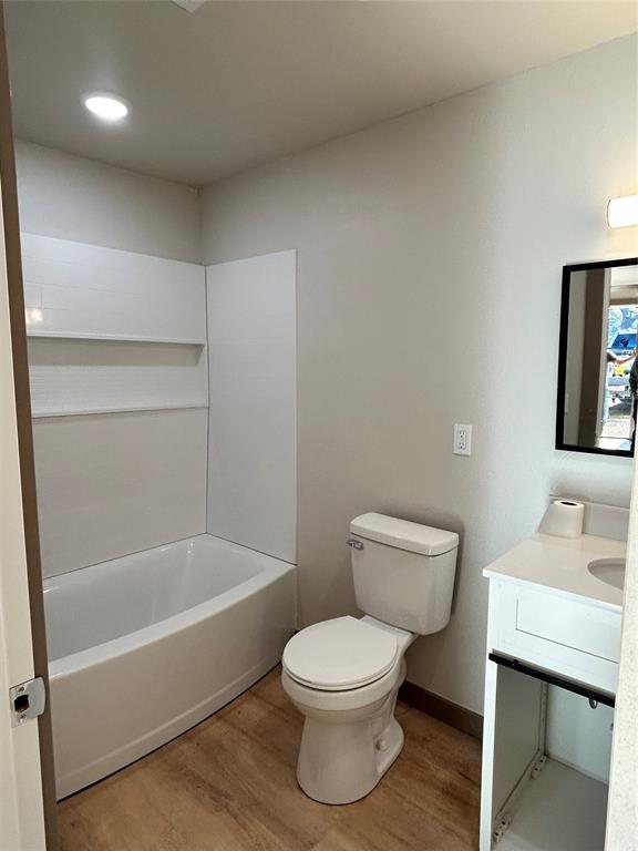 full bathroom with hardwood / wood-style floors, toilet, vanity, and shower / tub combination