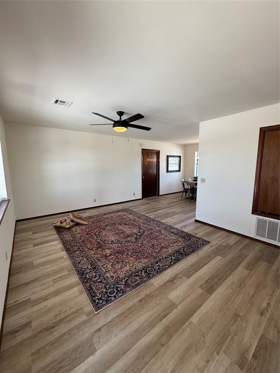 living area featuring visible vents, ceiling fan, and wood finished floors