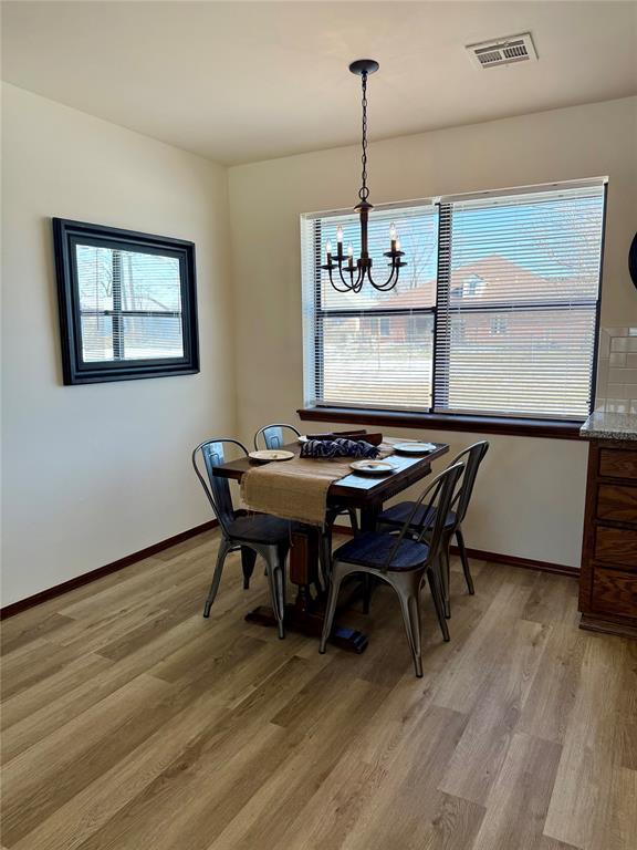 dining space with light wood-style floors, baseboards, visible vents, and a chandelier