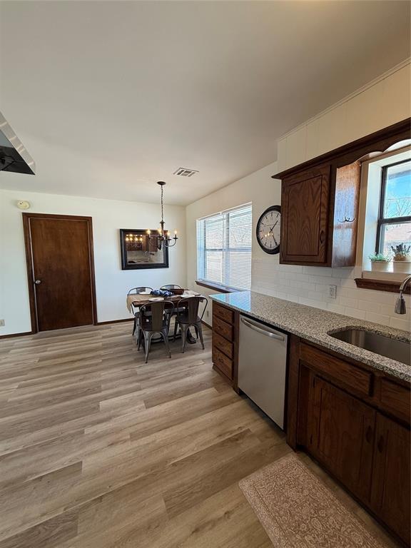 kitchen featuring dishwasher, a wealth of natural light, a sink, and light wood-style flooring