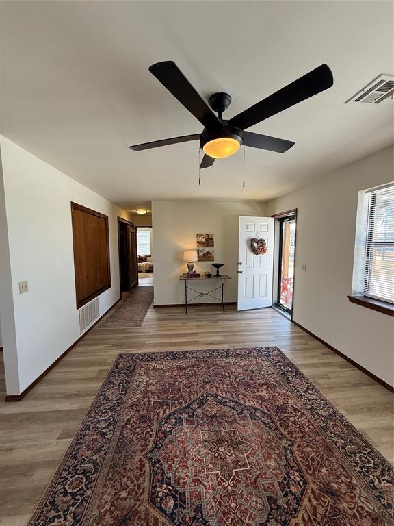 living room featuring wood finished floors, visible vents, and baseboards