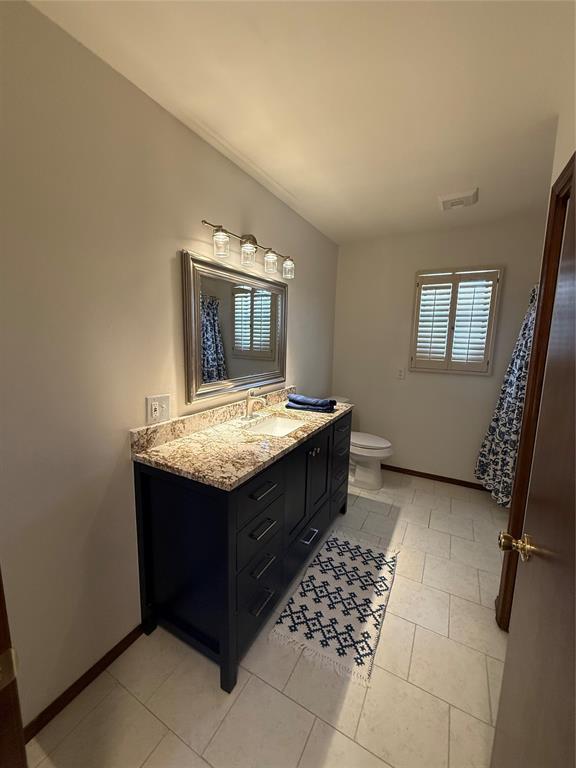 full bathroom with baseboards, vanity, and toilet