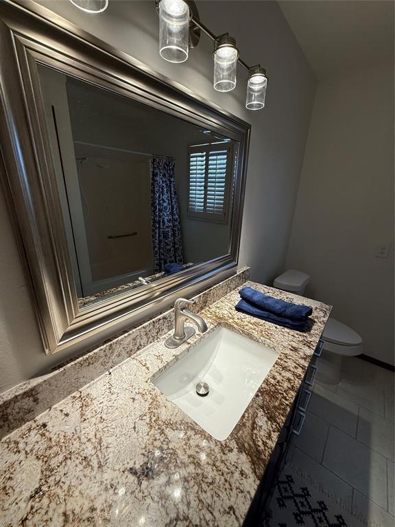 full bathroom with curtained shower, vanity, toilet, and baseboards