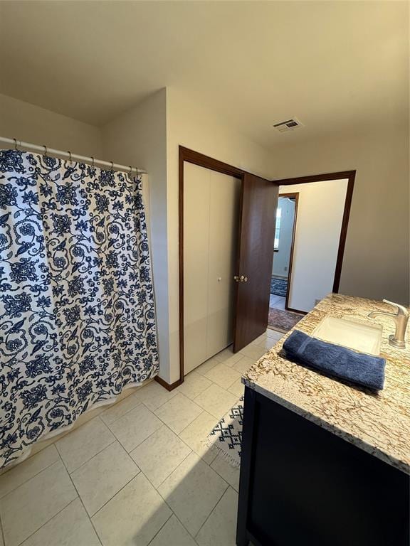 bedroom featuring a closet, visible vents, a sink, and light tile patterned floors