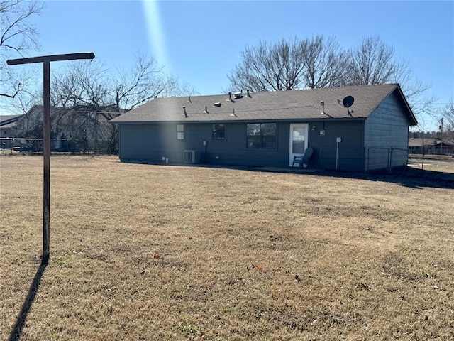 back of property featuring a yard, central AC unit, and fence