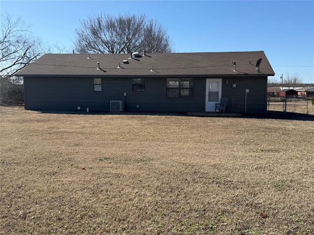 rear view of property with central AC unit, a lawn, and fence