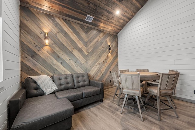 dining area featuring lofted ceiling, wood ceiling, wood-type flooring, and wooden walls