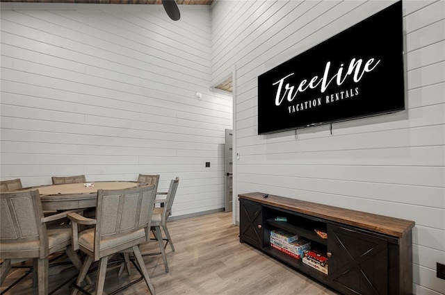 dining space featuring light hardwood / wood-style floors and wooden walls