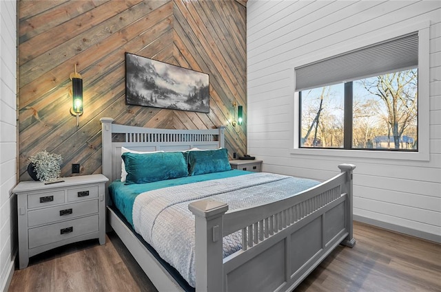 bedroom with dark hardwood / wood-style flooring and wooden walls