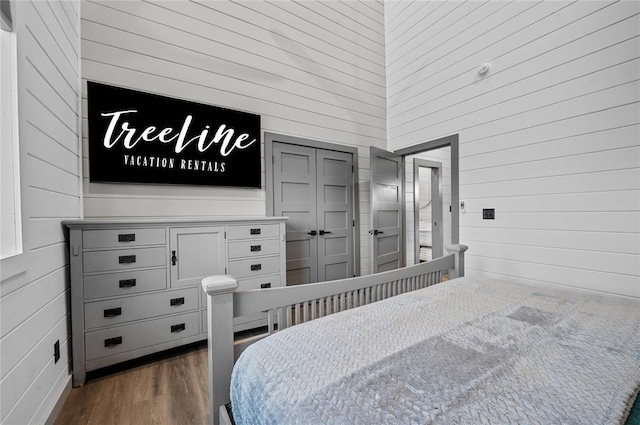 bedroom featuring dark hardwood / wood-style flooring and wooden walls