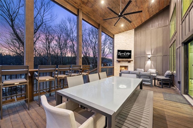 deck at dusk with ceiling fan and an outdoor living space with a fireplace