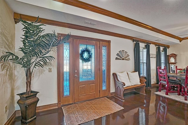 entryway with ornamental molding, a wealth of natural light, and a textured ceiling