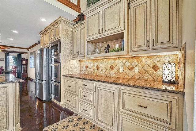 kitchen featuring crown molding, appliances with stainless steel finishes, decorative backsplash, and dark stone countertops