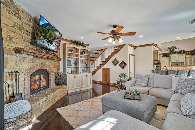 living room with ornamental molding, a large fireplace, hardwood / wood-style floors, and ceiling fan