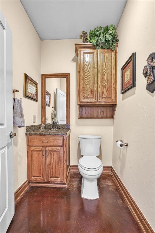 bathroom featuring vanity, concrete flooring, and toilet