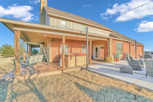 rear view of property featuring a patio area and a hot tub