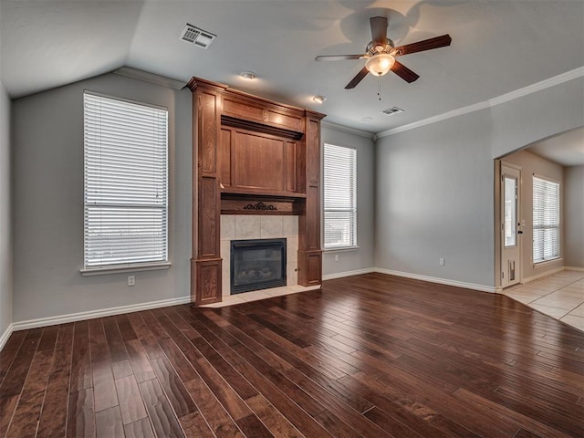 unfurnished living room with ceiling fan, a tile fireplace, lofted ceiling, and light wood-type flooring