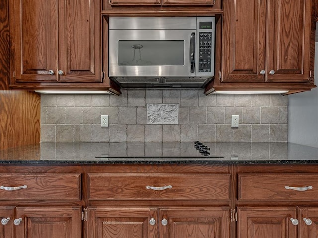 kitchen with decorative backsplash, black electric cooktop, and dark stone counters