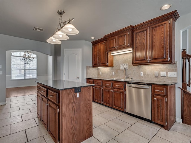 kitchen with an inviting chandelier, decorative light fixtures, a kitchen island, stainless steel dishwasher, and sink