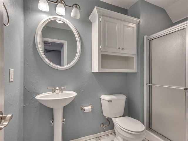 bathroom featuring sink, toilet, and a shower with door