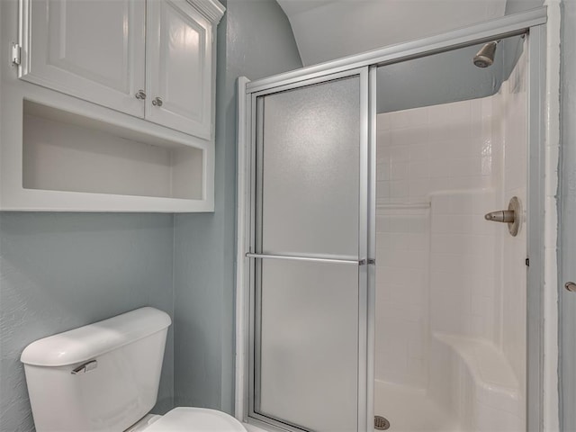 bathroom with a shower with shower door and toilet