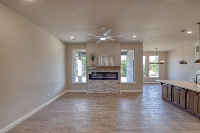 unfurnished living room with light hardwood / wood-style floors and ceiling fan with notable chandelier