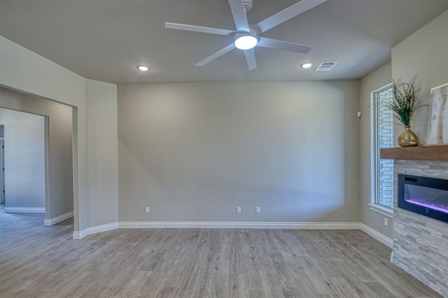 unfurnished living room with ceiling fan, light hardwood / wood-style floors, and a fireplace