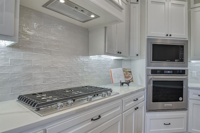 kitchen with light stone countertops, white cabinets, stainless steel appliances, and tasteful backsplash