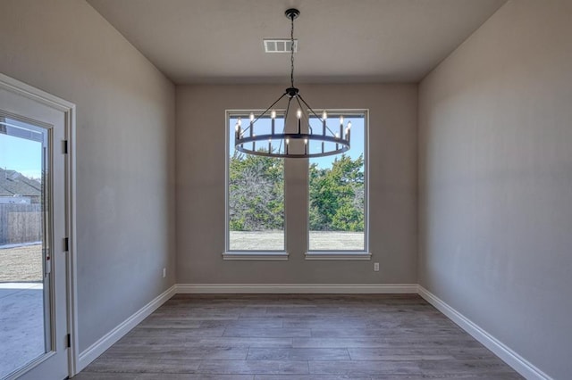 unfurnished dining area featuring plenty of natural light, dark hardwood / wood-style flooring, and an inviting chandelier