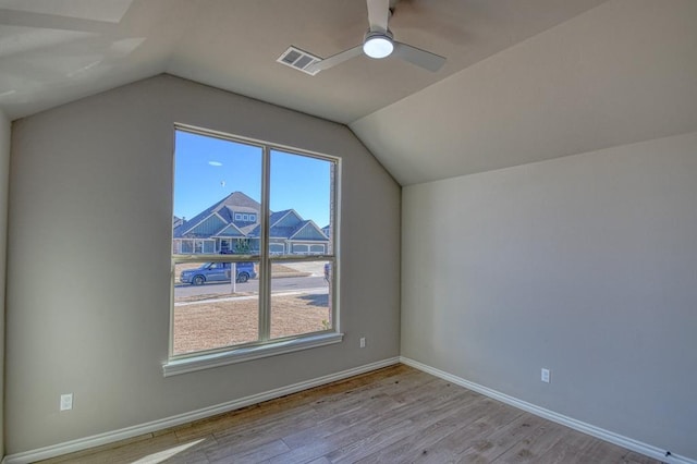 additional living space featuring light wood-type flooring, lofted ceiling, and a healthy amount of sunlight